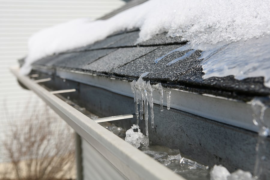 icy snow covered gutters and asphalt roof shingles