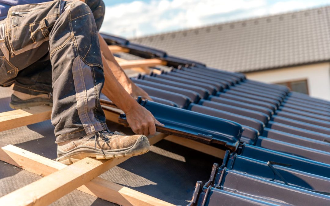 roofer installs a ceramic tile on the wooden frame of a new roof